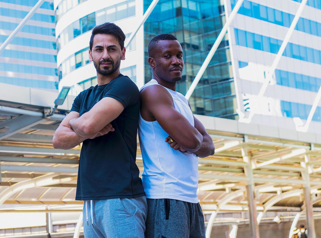 Deux beaux hommes portant des vêtements de sport réchauffent leur corps avant de faire de l'exercice à l'extérieur en ville photo