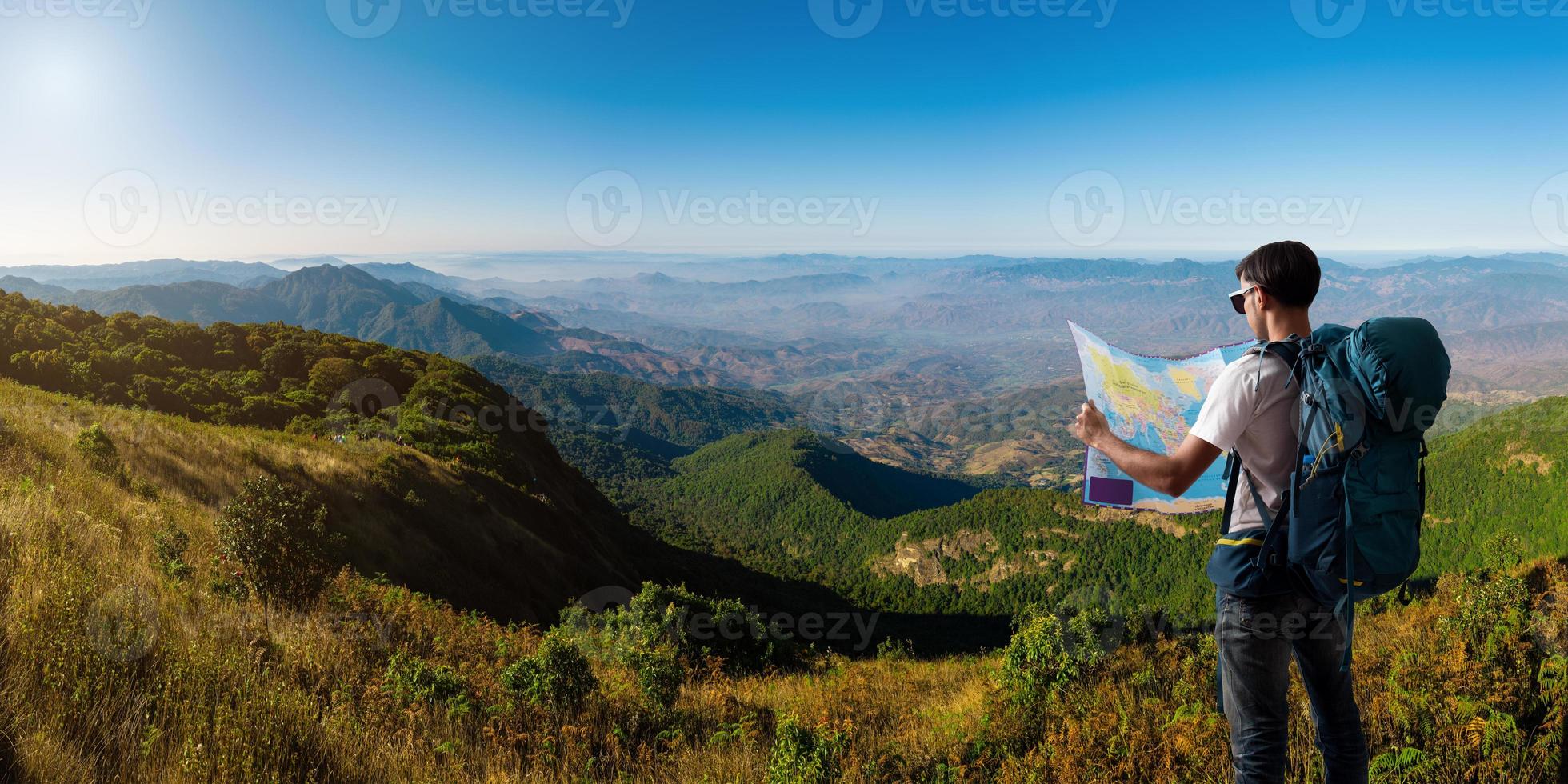 voyageur avec carte sac à dos relaxant en plein air avec des montagnes photo