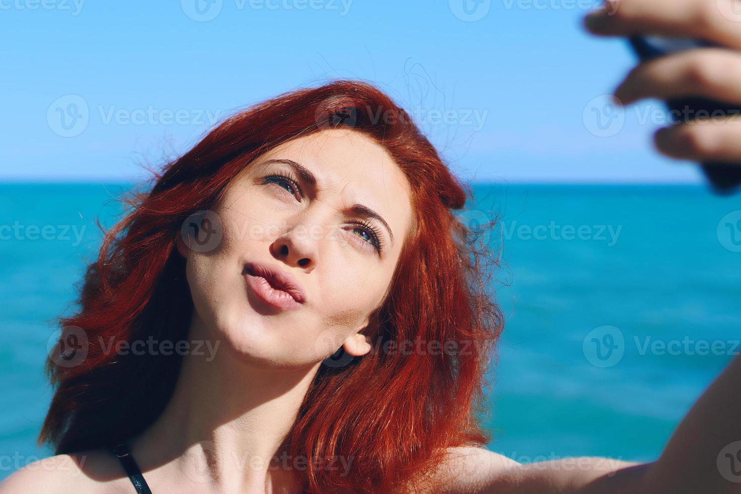 Femme rousse prend selfie sur la caméra du smartphone photo