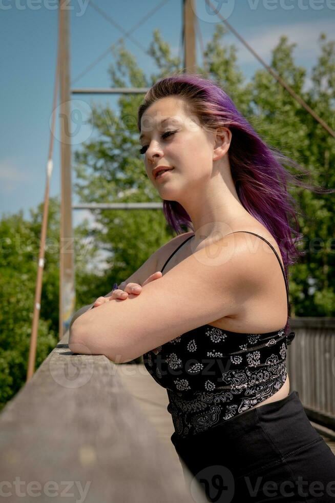 Jeune femme avec violet cheveux sur une pont dans le vent photo