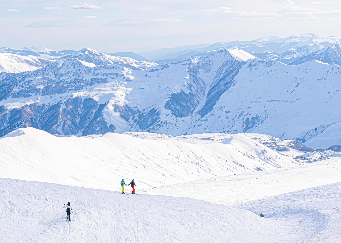 Vue panoramique sur les montagnes du Caucase avec trois skieurs sur la colline posant photo