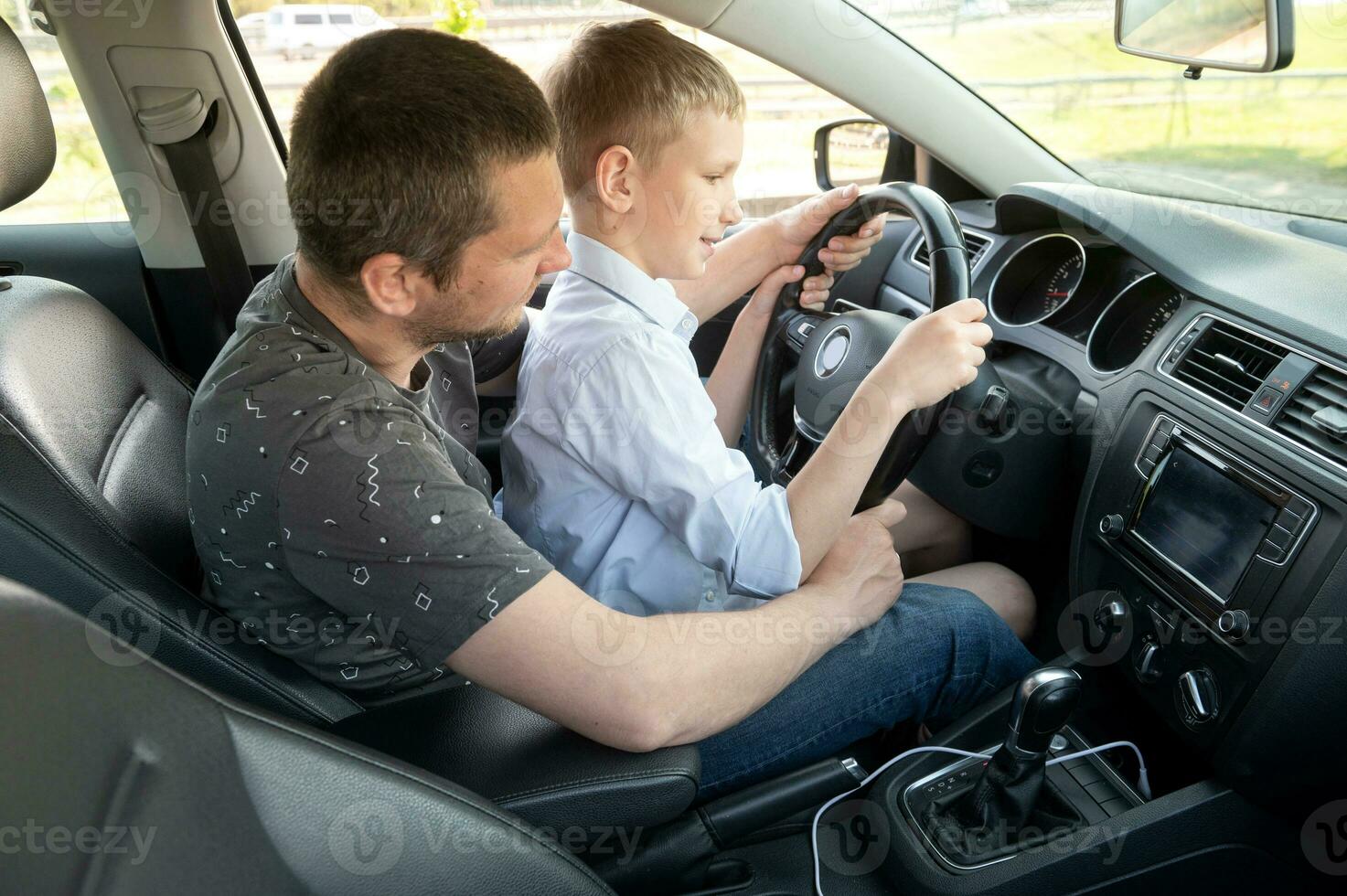 papa enseigne le garçon à conduire une auto. le enfant détient le pilotage roue et départs le voiture photo