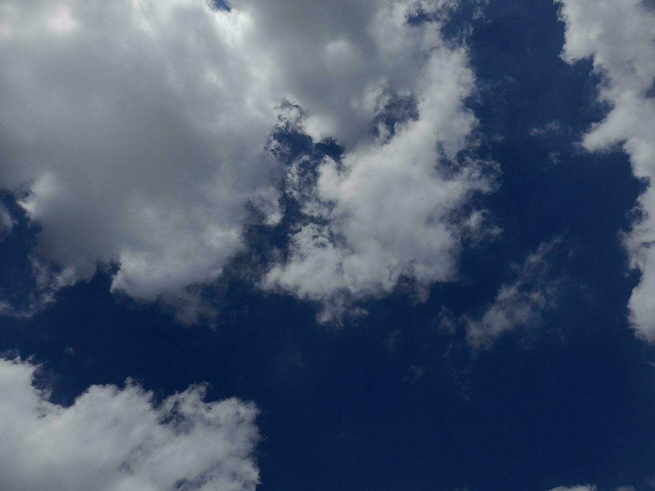 nuages blancs dans le ciel bleu. beau fond bleu clair. peu nuageux, beau temps. nuages bouclés par une journée ensoleillée. photo