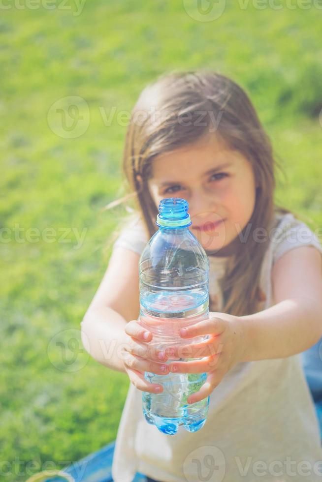 petite fille tient une bouteille deau photo