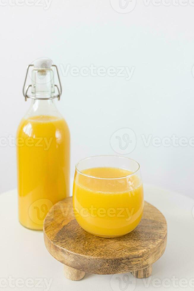 Frais pressé Orange jus dans bouteille et verre sur table sur blanc Contexte. en bonne santé boisson photo