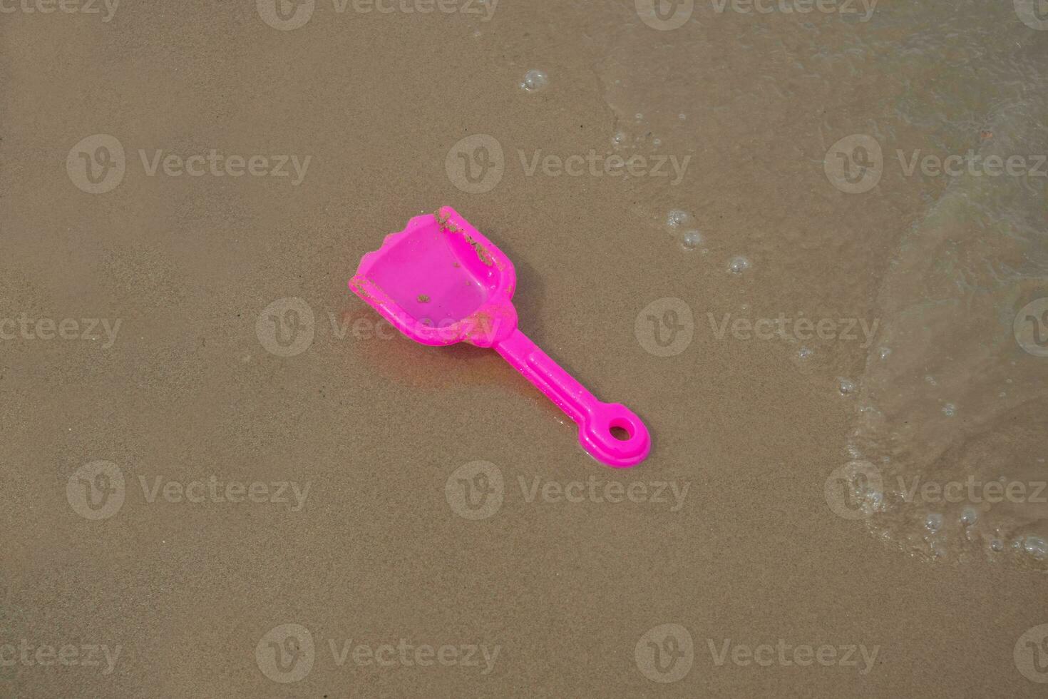 rose jouet Plastique pelle sur plage le sable et vagues. concept photo pour été temps