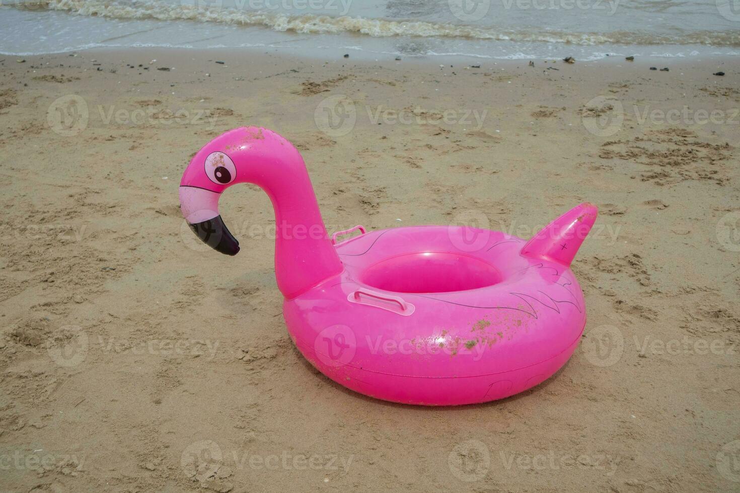 une rose en forme de flamant rose bouée sur le plage sable. été concept photo