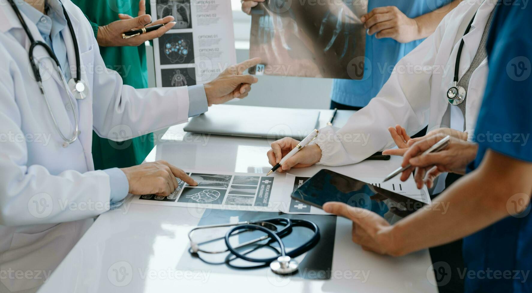 médical équipe ayant une réunion avec médecins dans blanc laboratoire manteaux et chirurgical gommages assise à une table discuter une les patients travail en ligne en utilisant des ordinateurs dans le médical industrie photo
