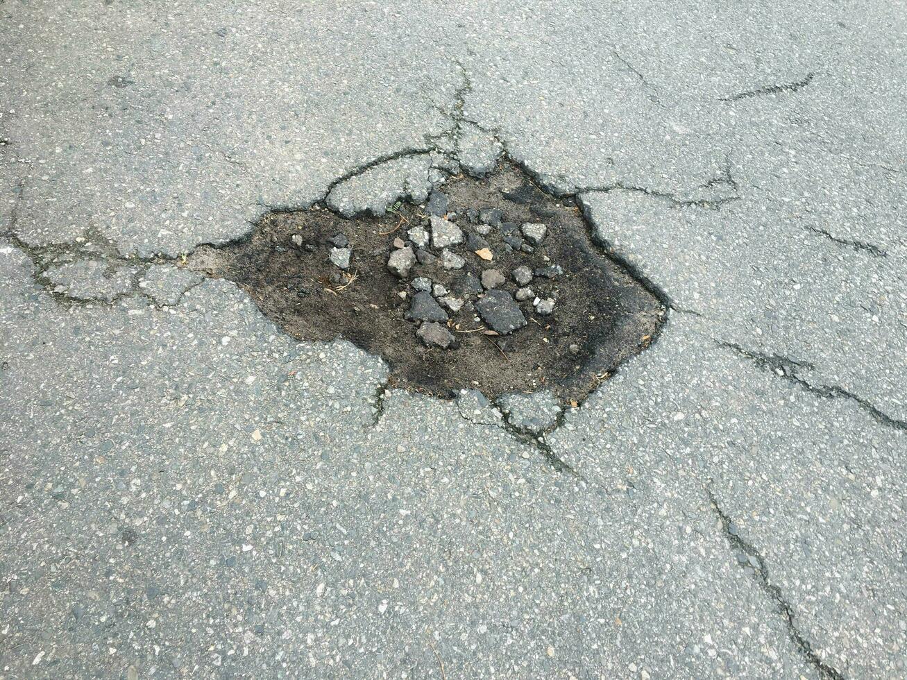 le texture de fissuré vieux asphalte. grand nid de poule dans pays asphalte route photo