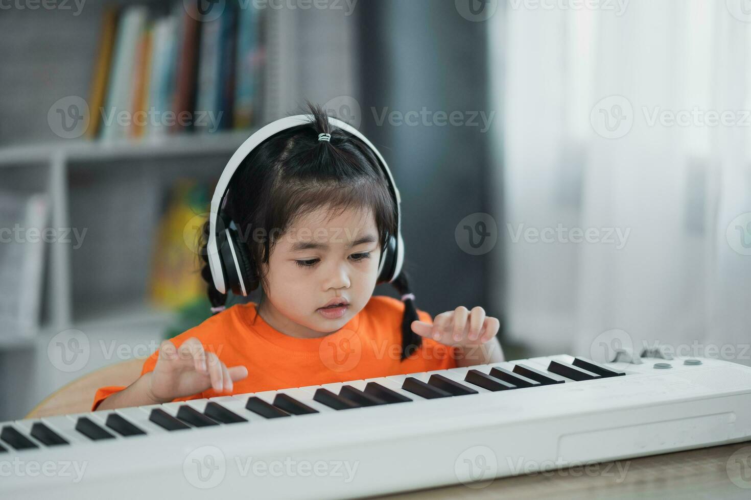 asiatique mignonne fille portant casque de musique apprentissage en ligne piano la musique avec prof par mobile téléphone ou tablette. le idée de Activités pour le enfant à Accueil pendant quarantaine. la musique apprentissage étude concept. photo