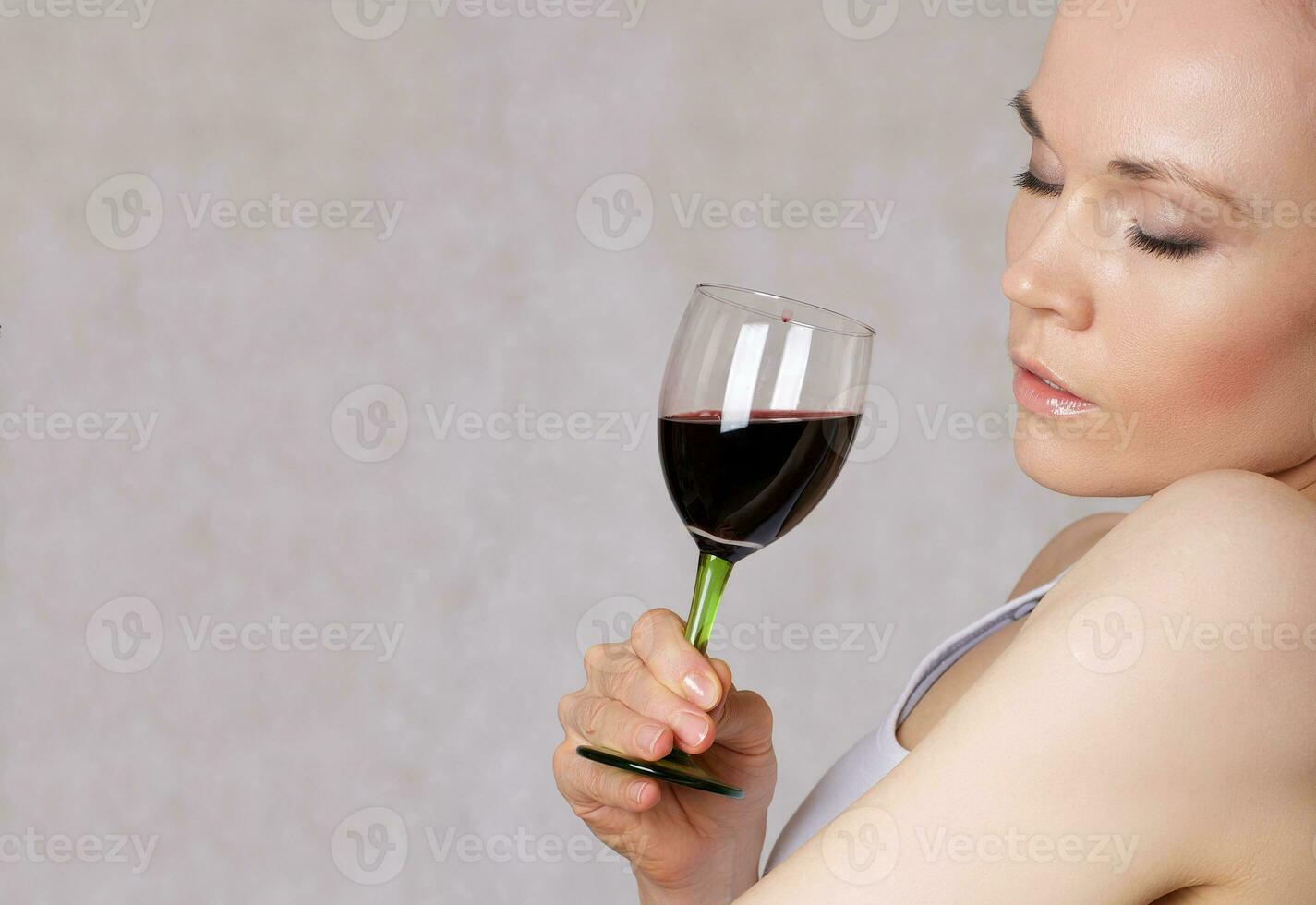Jeune Dame garde une verre de rouge du vin dans sa main photo