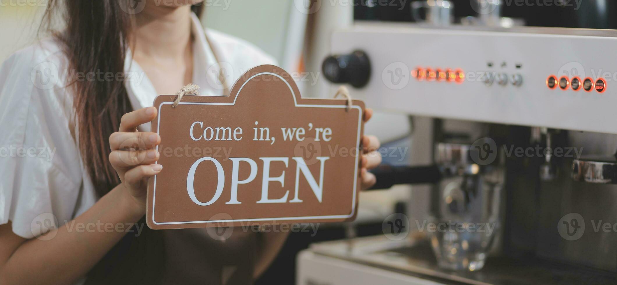 ouvrir. barista, serveuse femme portant un masque de protection tournant un panneau d'affichage ouvert sur une porte en verre dans un café moderne, un café-restaurant, un magasin de détail, un propriétaire de petite entreprise, un concept de nourriture et de boisson photo