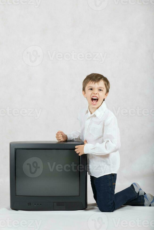 garçon de Sept ans vieux veut à détruire un vieux la télé. photo
