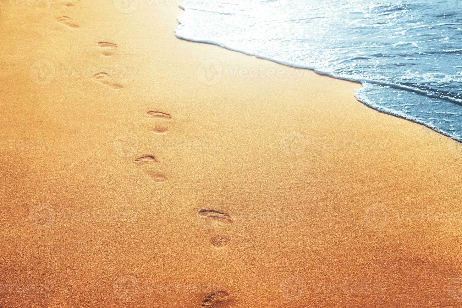 marchant sur la plage, laissant des empreintes de pas dans le sable. photo