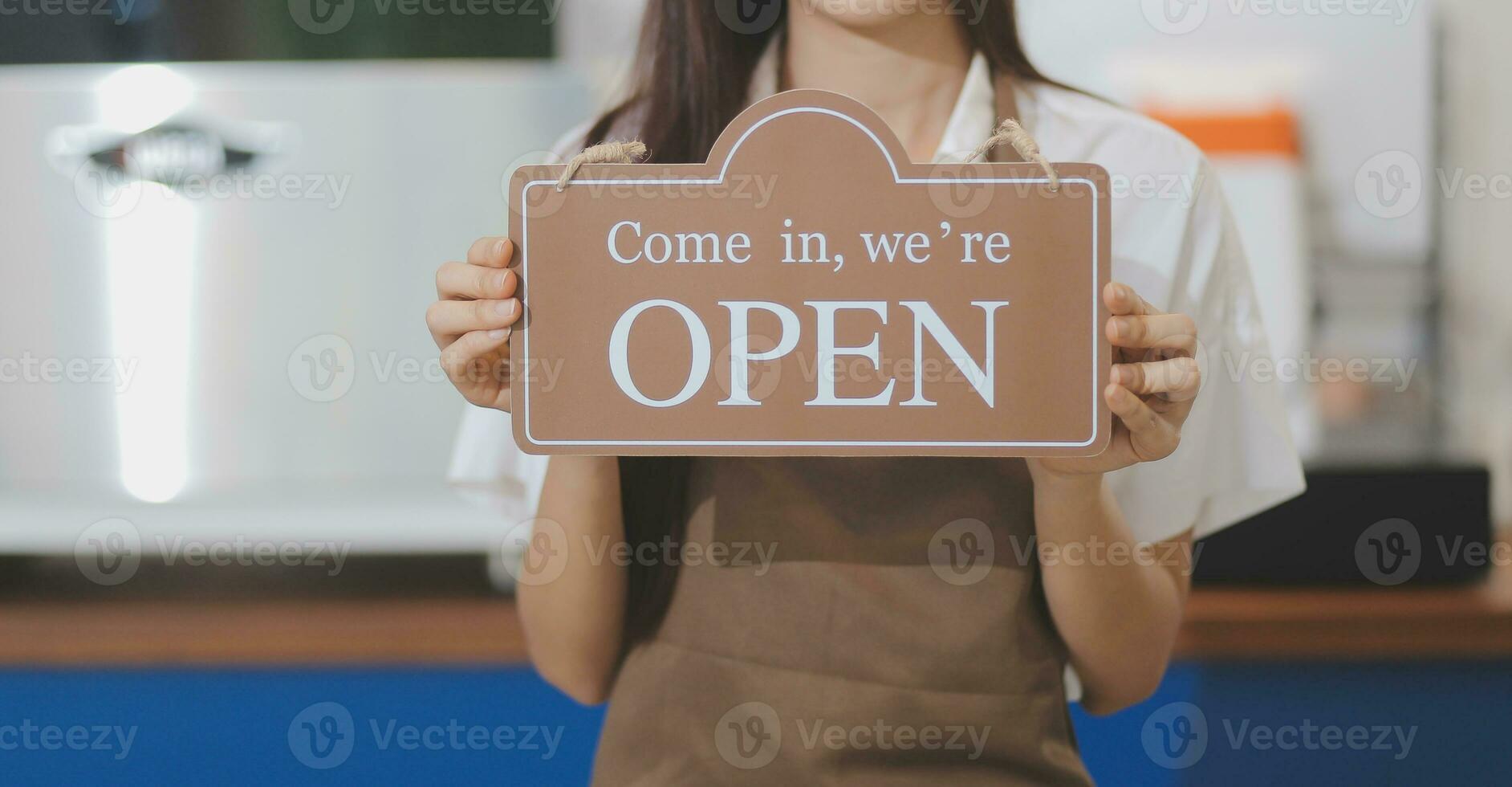 Bienvenue. ouvert. barman, serveuse femme tournant ouvert signe planche sur verre porte dans moderne café café magasin prêt à service, café restaurant, vente au détail magasin, petit affaires propriétaire, nourriture et boisson concept photo