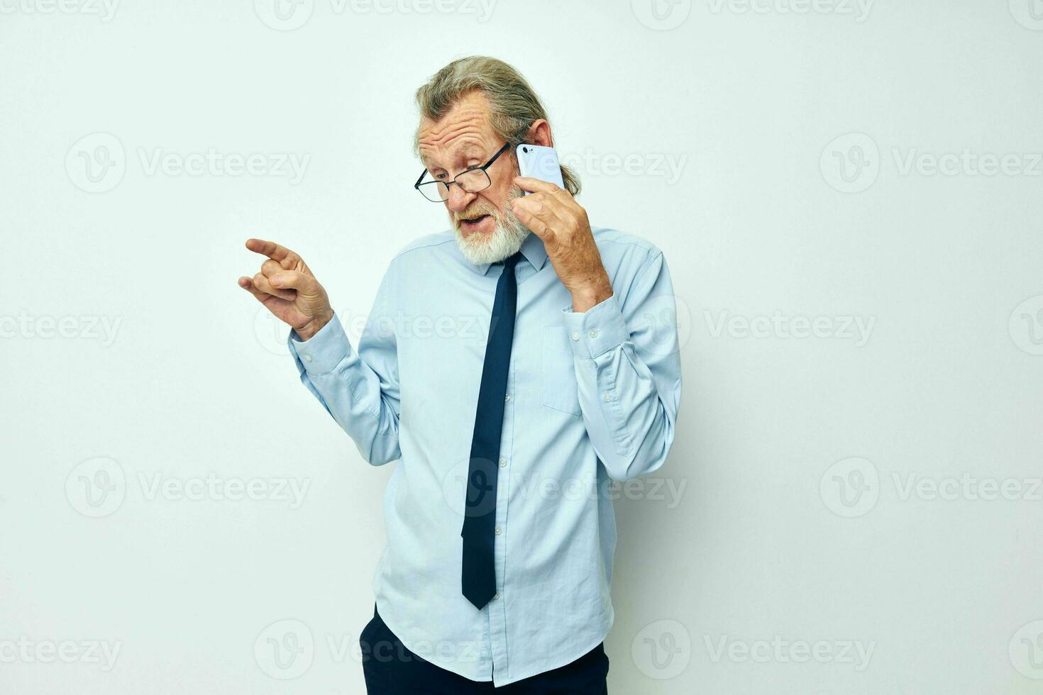 Sénior aux cheveux gris homme dans une chemise avec une attacher avec une téléphone La technologie tondu vue photo