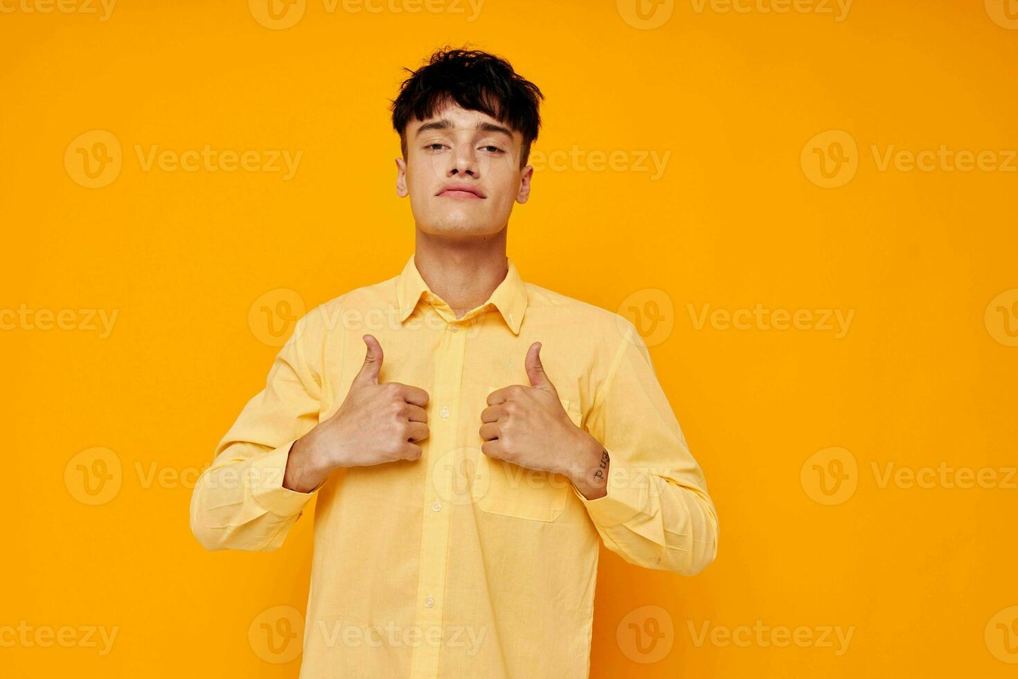 de bonne humeur Jeune homme dans une Jaune chemise gestes avec le sien mains émotions photo