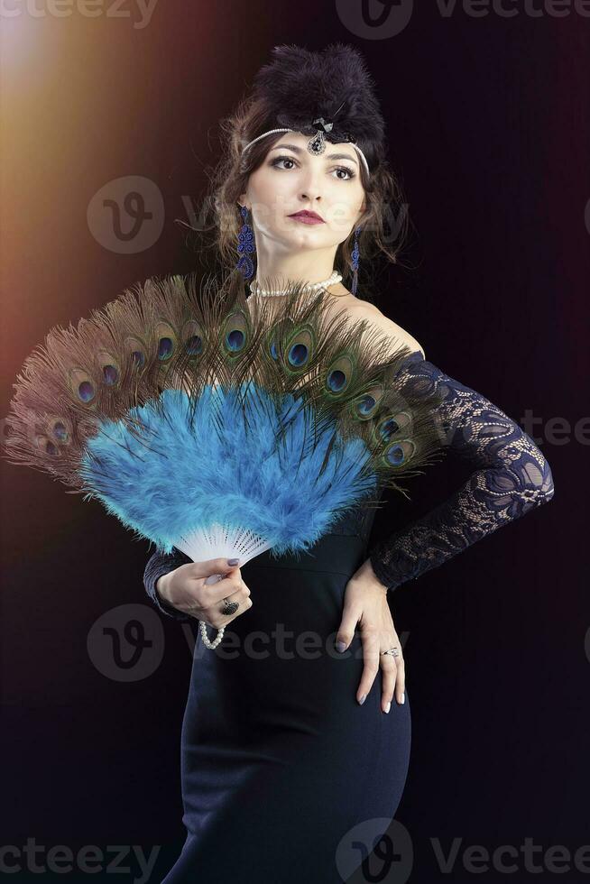 rétro femme portrait. magnifique fille avec une ventilateur dans le style de le Années 20 ou 30s. vieux à la mode doigt vague maquillage et coiffure. photo