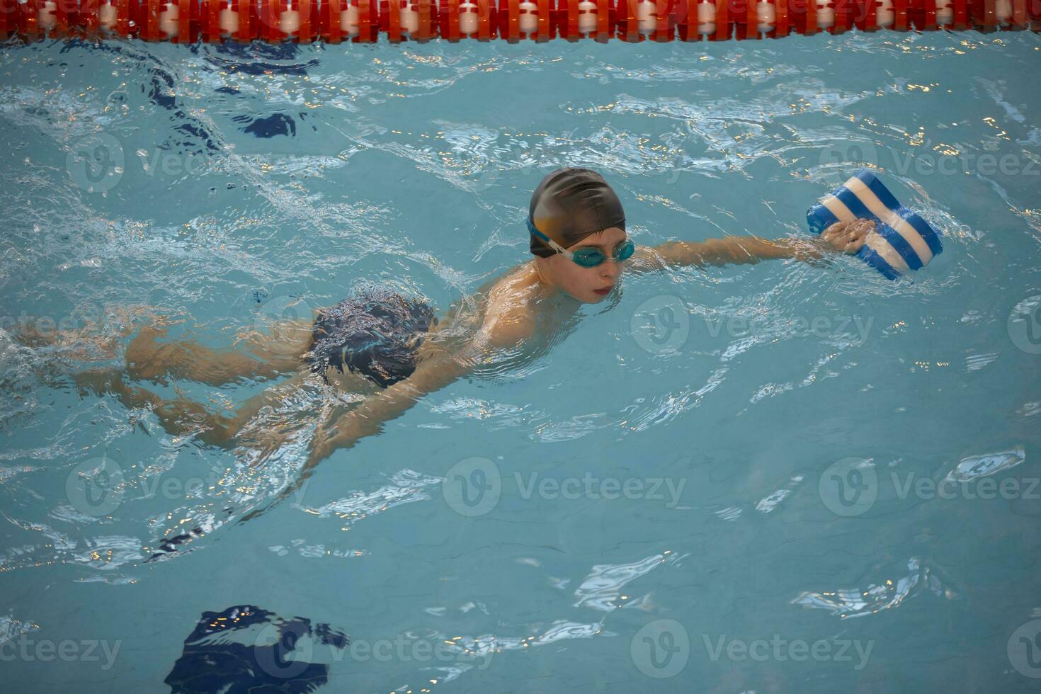 garçon dans une nager casquette et nager des lunettes de protection dans le bassin. le enfant est engagé dans le nager section. photo