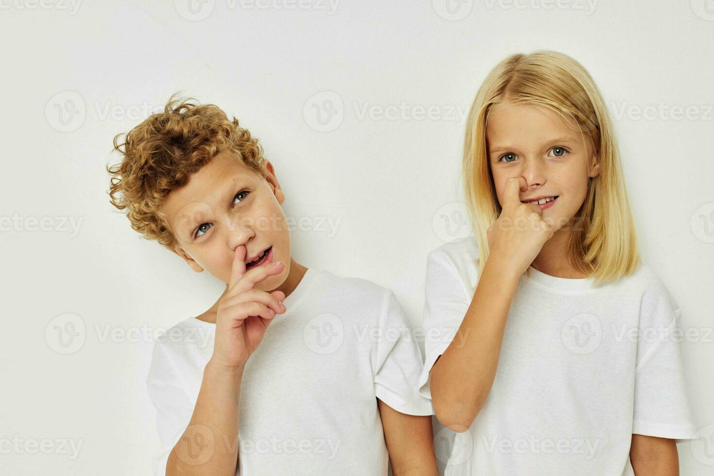 photo de deux les enfants dans blanc t-shirts sont permanent suivant à beige Contexte