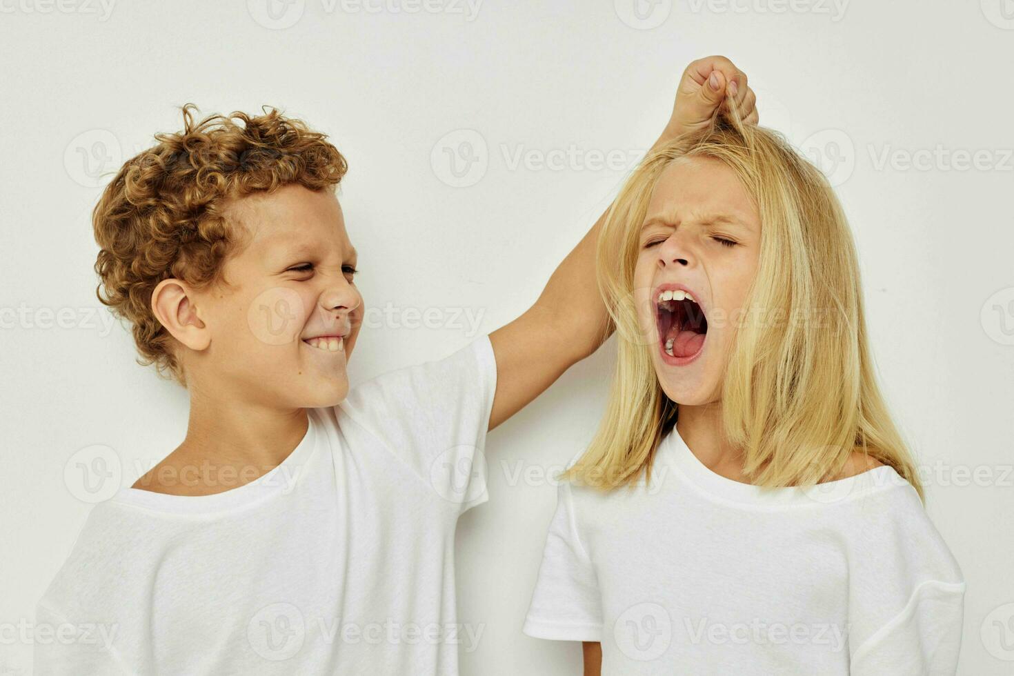 garçon et fille dans blanc t-shirts sont permanent suivant à isolé Contexte photo
