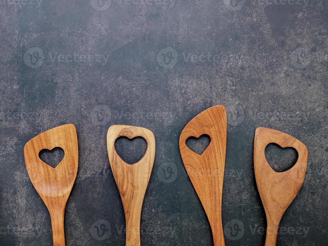 Diverses formes de coeur d'ustensiles de cuisine en bois cuillères en bois et spatule en bois sur fond de béton avec mise à plat et espace de copie photo