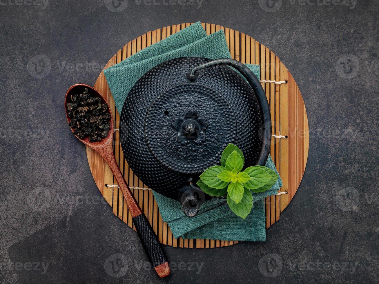 Théière en fonte noire avec tisane mis en place sur fond de pierre sombre photo