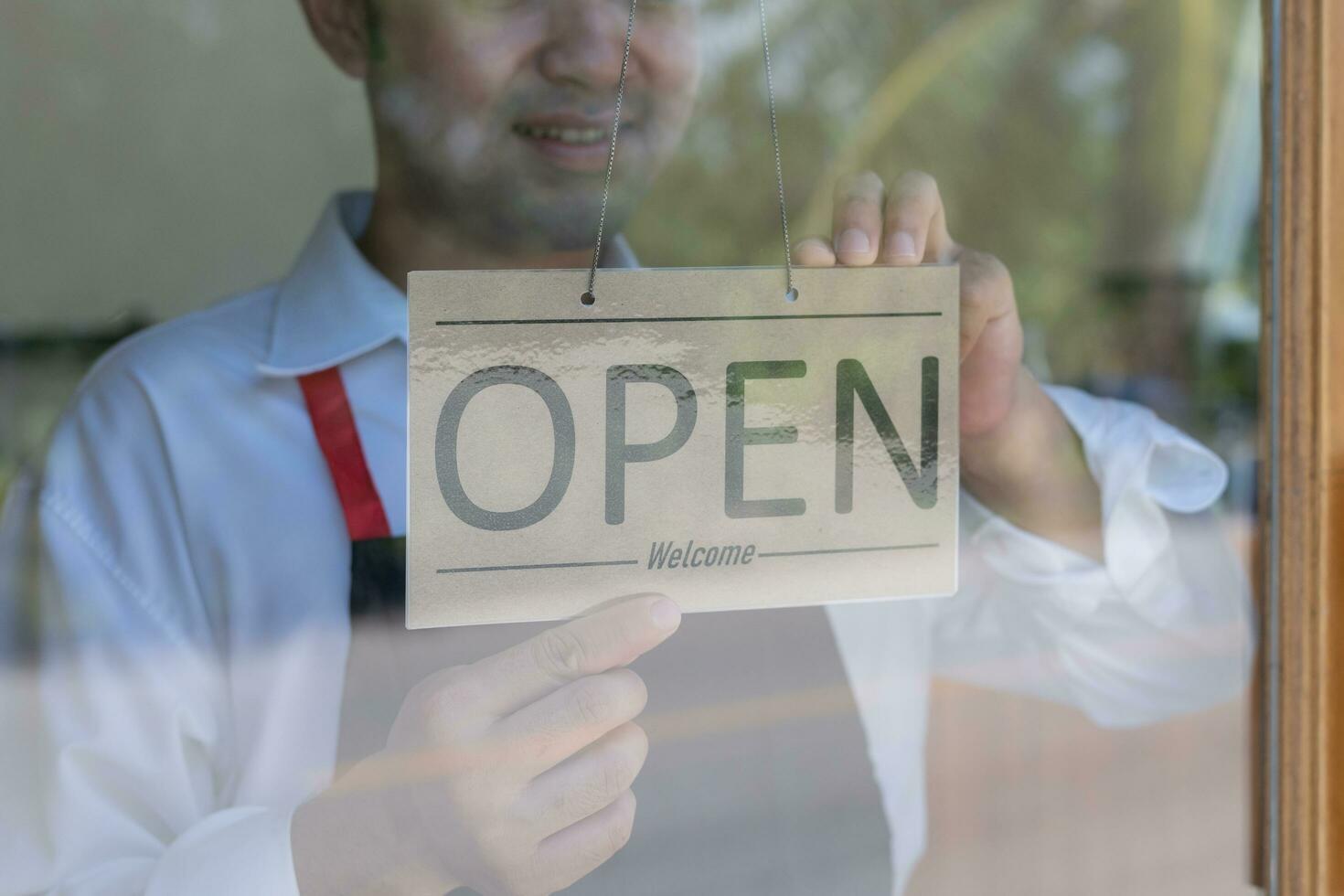 propriétaire modifié le signe de fermé à ouvert sur le premier journée de entreprise. garanties sécurité, propreté, protecteur masques et ouvert le café magasin. ouvert pour Nouveau Ordinaire concept. photo