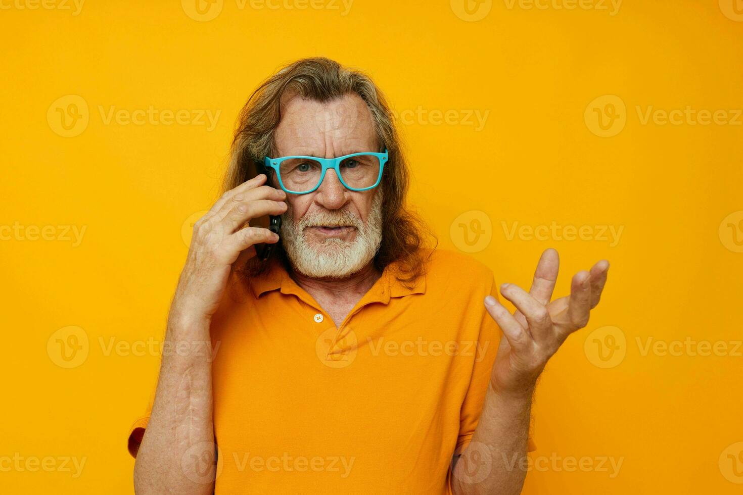 vieux homme dans Jaune t-shirts et des lunettes parlant sur le téléphone isolé Contexte photo