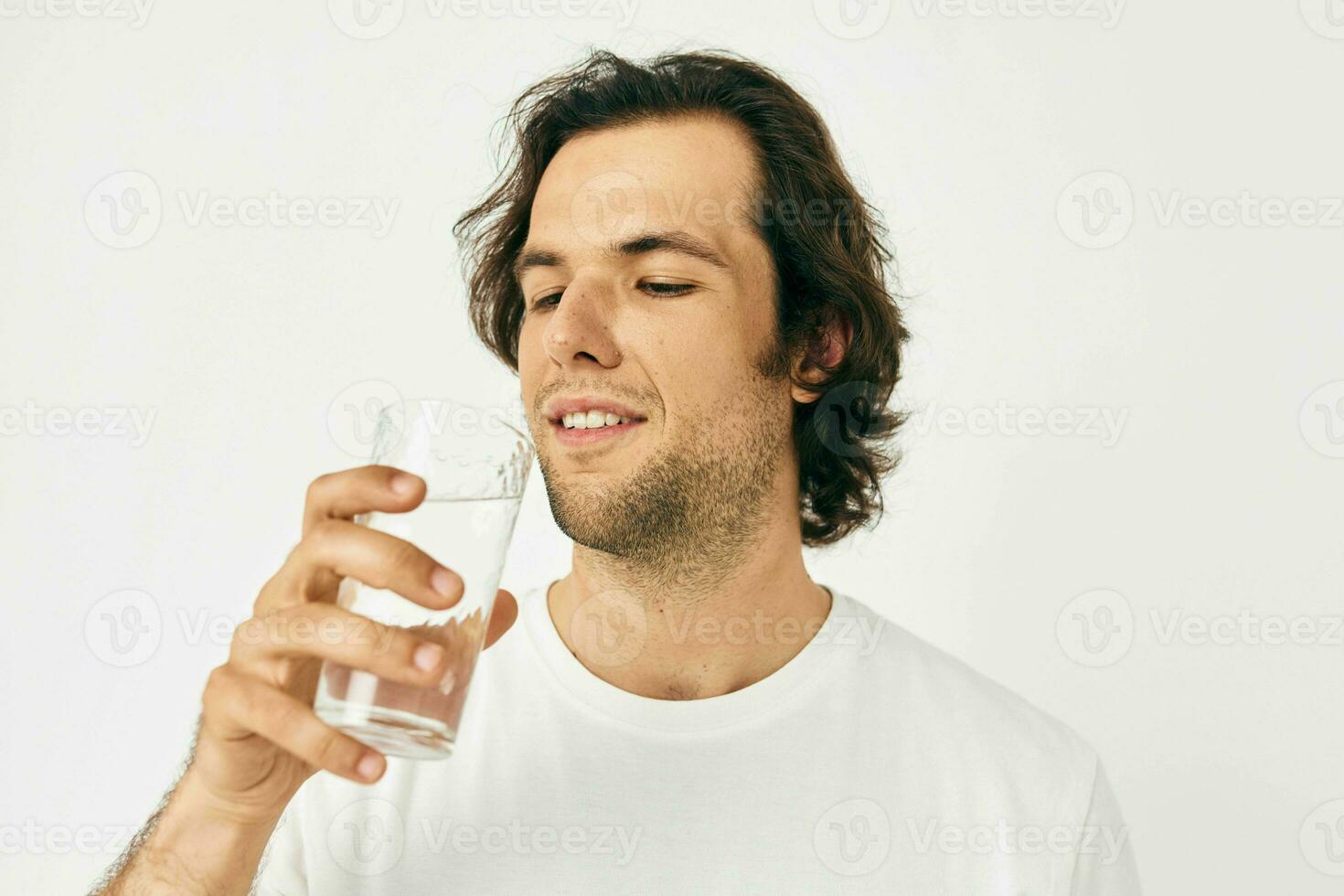 attrayant homme dans une blanc T-shirt verre de l'eau isolé Contexte photo