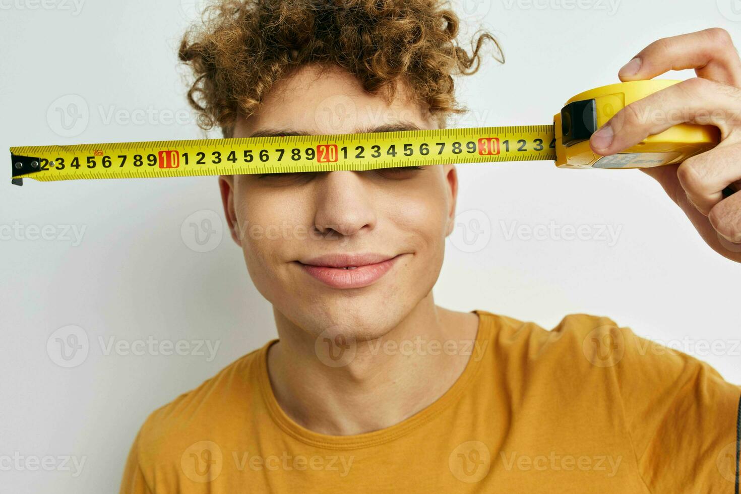 Beau gars mesure ruban mesure dans Jaune T-shirt lumière Contexte photo