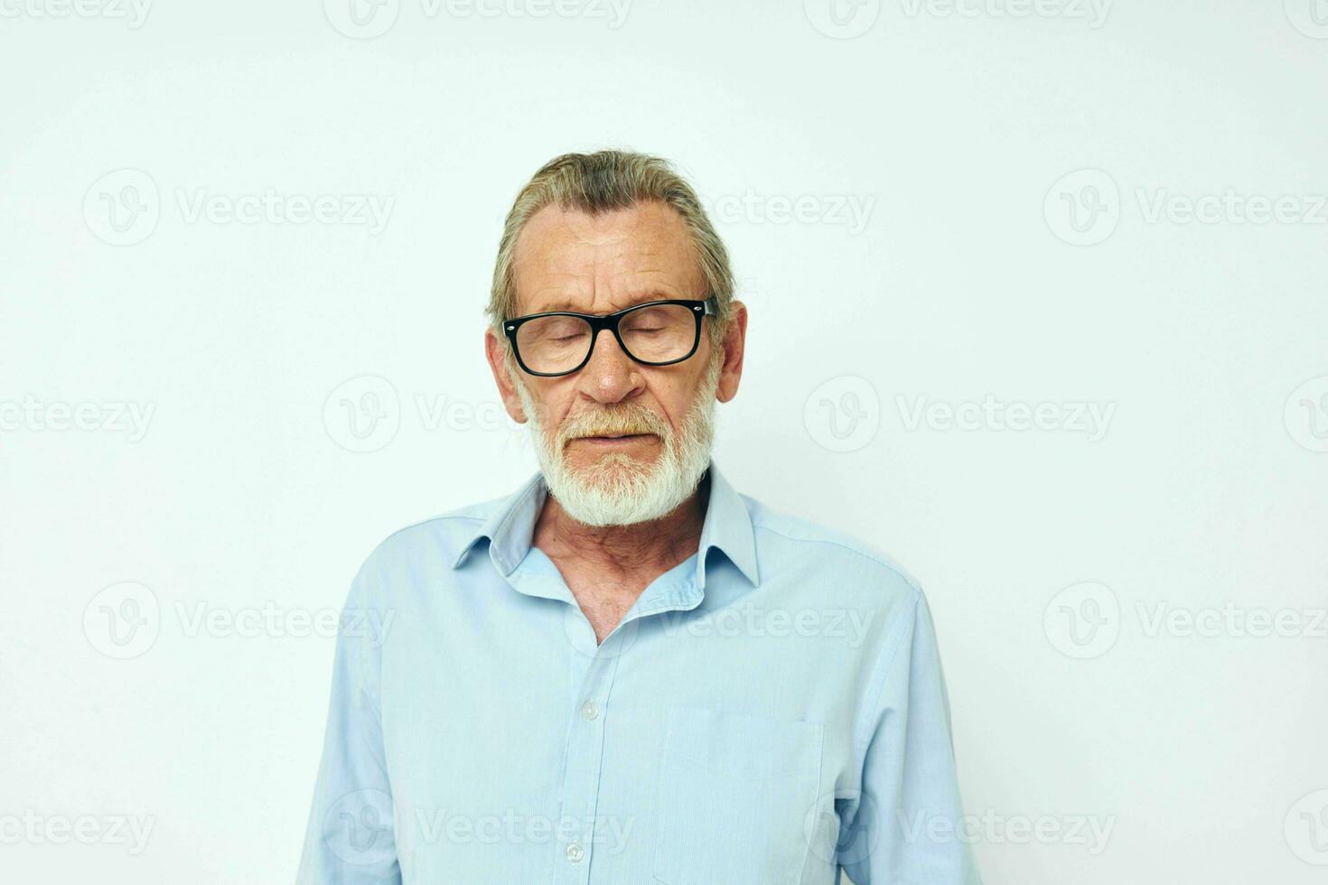 Sénior aux cheveux gris homme dans bleu chemises gestes avec le sien mains lumière Contexte photo