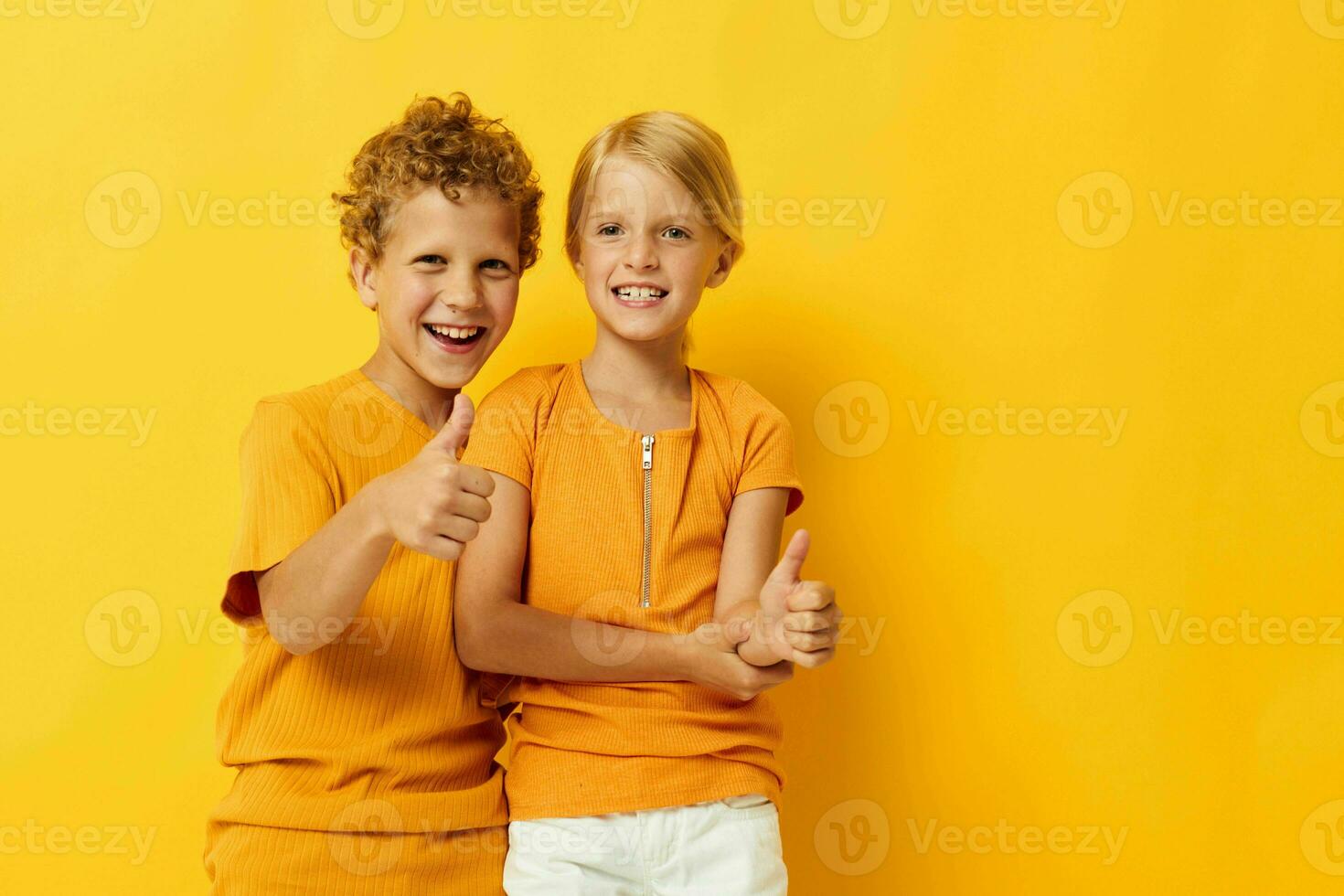 mignonne élégant des gamins dans Jaune t-shirts permanent côté par côté enfance émotions isolé Contexte inchangé photo