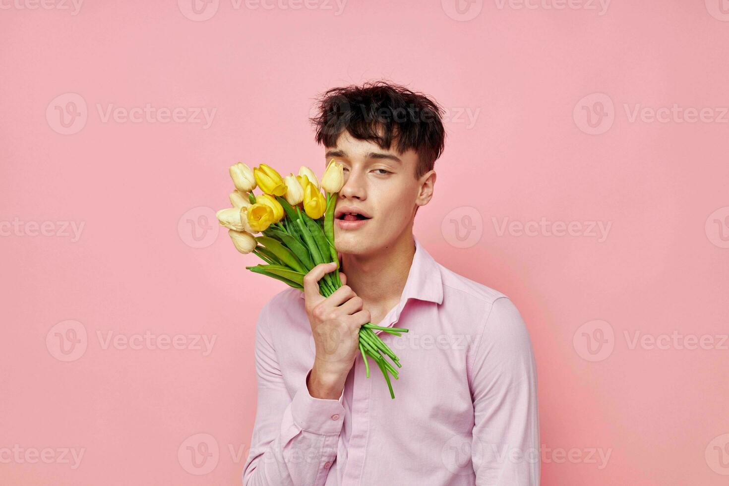 jolie homme dans une rose chemise avec une bouquet de fleurs faire des gestes avec le sien mains modèle studio photo