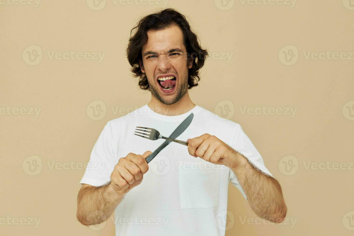 Beau homme dans une blanc T-shirt avec couteau avec fourchette isolé Contexte photo