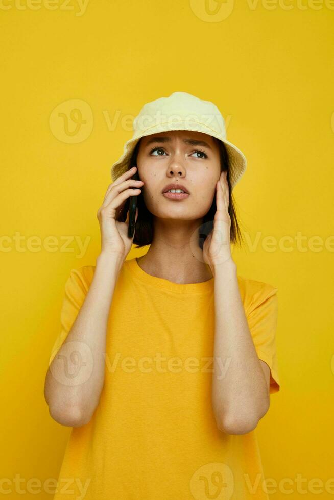 Jeune femme dans une Jaune chapeau jeunesse style décontractée parlant sur le téléphone isolé Contexte photo