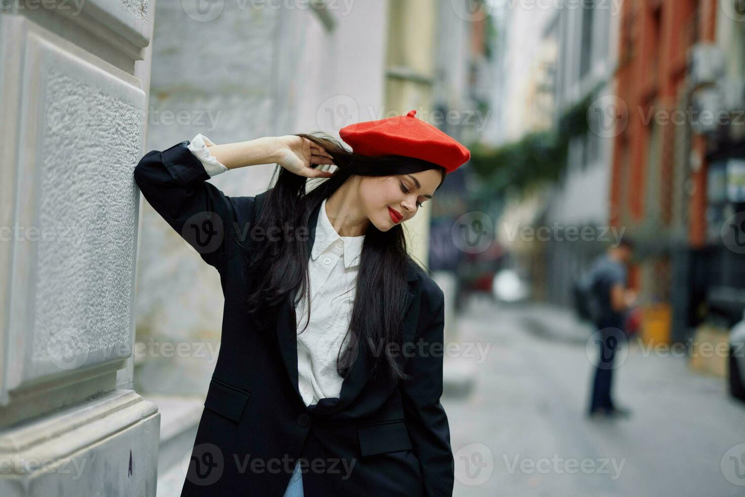 femme permanent près une mur dans le ville portant une élégant veste et rouge béret avec rouge lèvres, Voyage et loisirs, français style de robe. photo