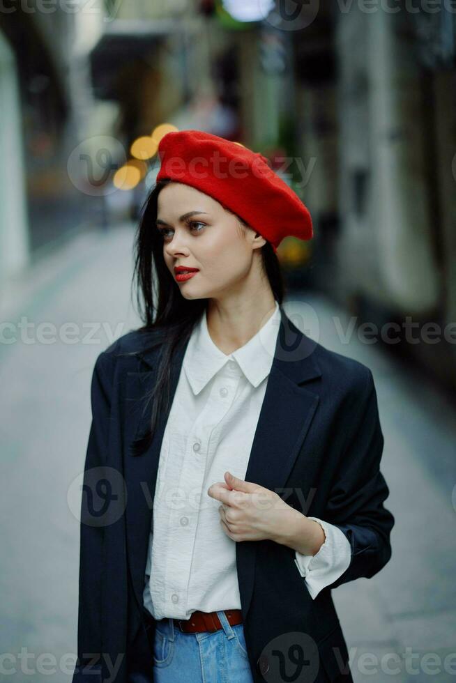 mode femme sourire avec les dents portrait en marchant touristique dans élégant vêtements dans veste avec rouge lèvres en marchant vers le bas étroit ville rue en volant cheveux, voyage, cinématique couleur, rétro ancien style. photo