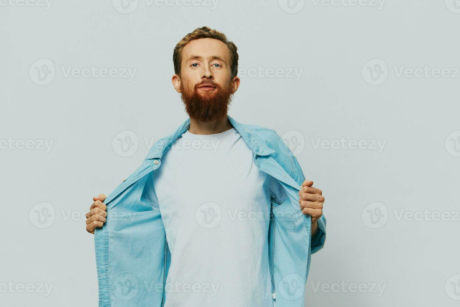 Masculin branché portrait sourire sur gris Contexte dans bleu chemise et blanc T-shirt, portrait de une homme avec une barbe photo