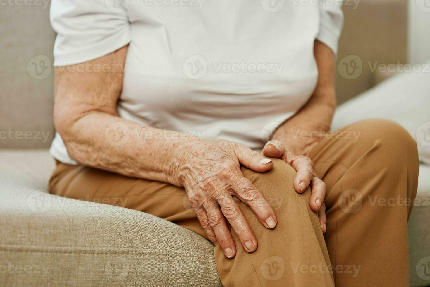 personnes âgées femme sévère douleur dans sa jambe séance sur le canapé, santé problèmes dans vieux âge, pauvres qualité de vie. grand-mère avec gris cheveux détient sur à sa endolori genou, problèmes avec les articulations et ligaments. photo