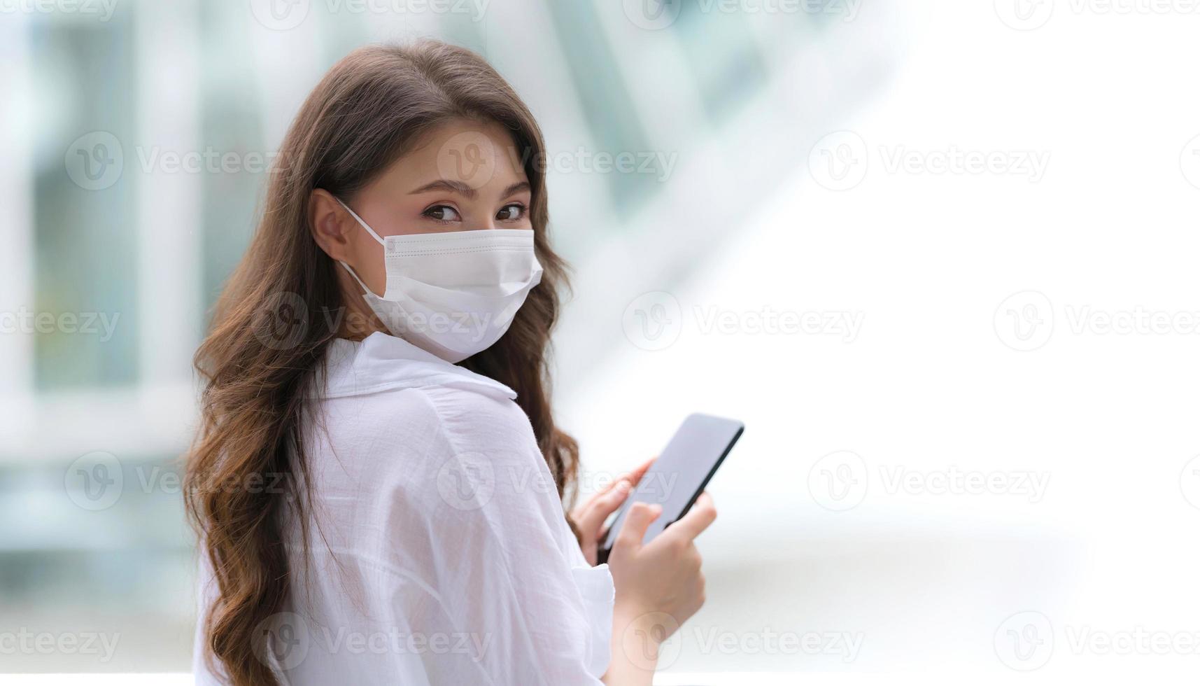 Portrait de jeune femme avec visage souriant à l'aide d'un téléphone se promène dans une ville photo