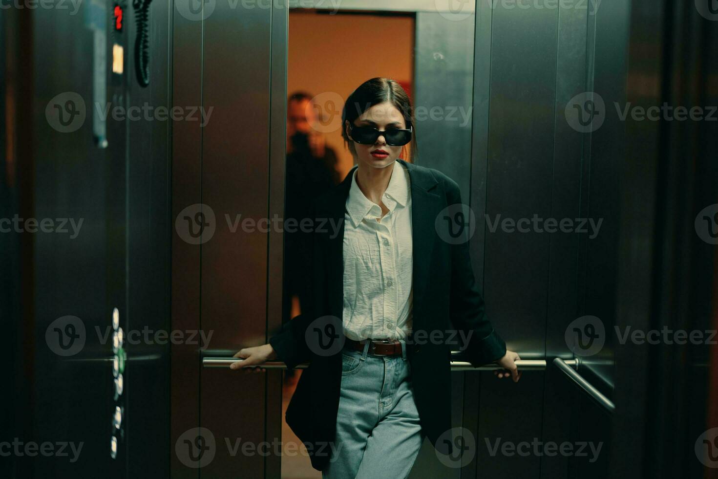 élégant femme dans noir veste et des lunettes de soleil posant dans ascenseur, mode modèle, foncé cinématique lumière et couleur, charme ancien photo