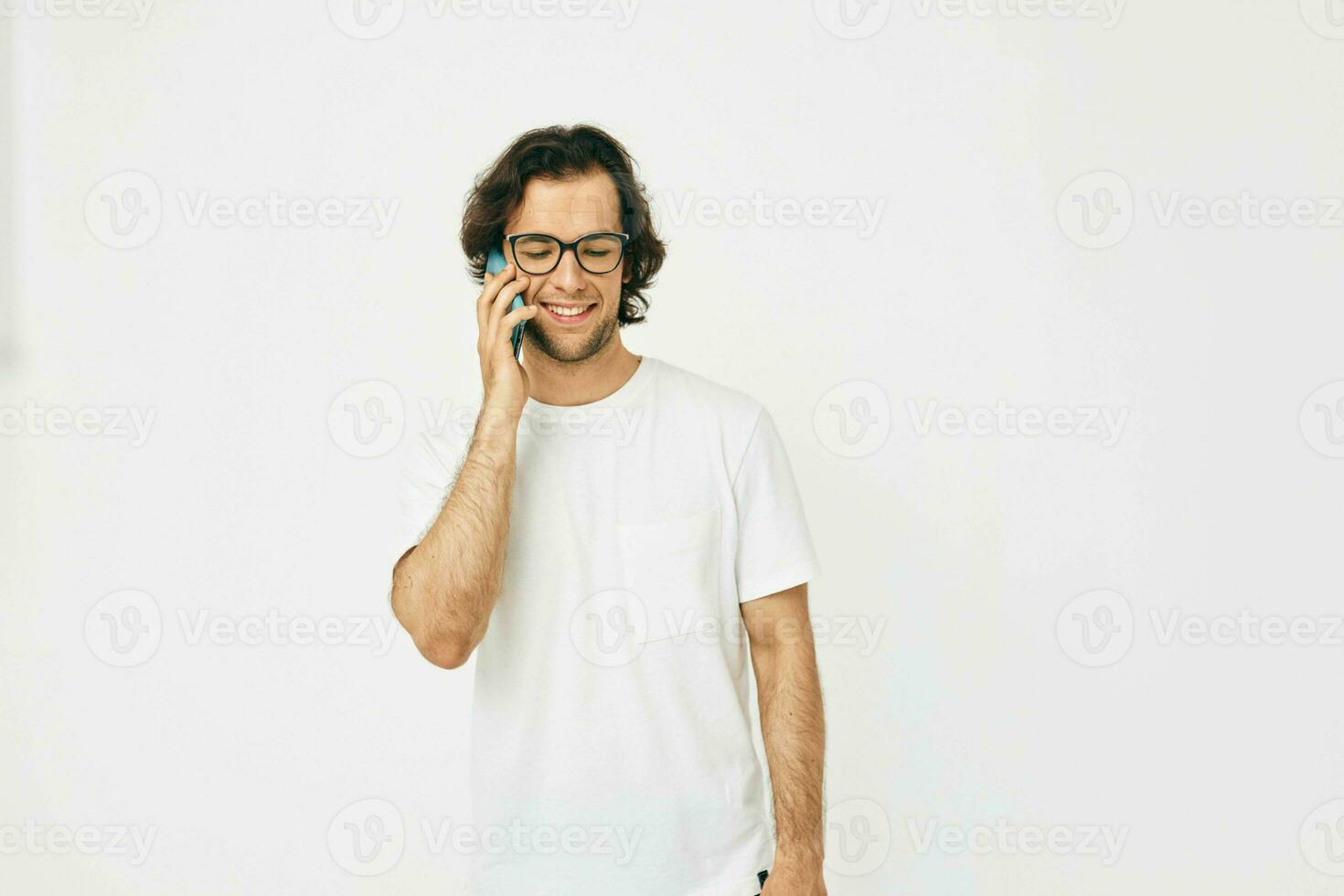 attrayant homme dans une blanc T-shirt la communication par téléphone isolé Contexte photo
