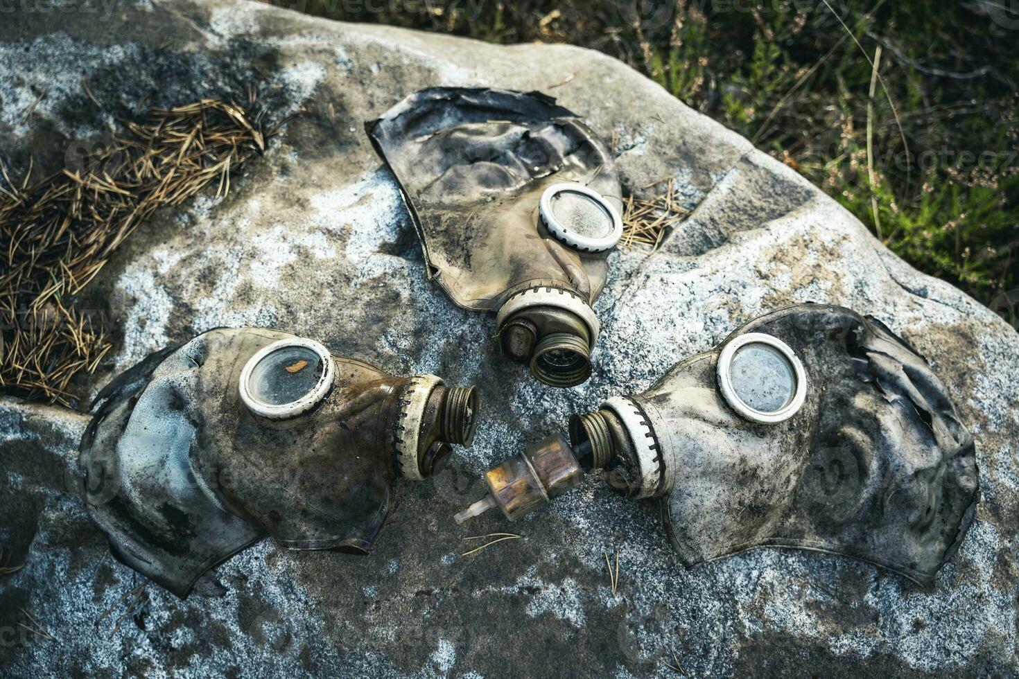 Trois vieux utilisé gaz masques sont mensonge sur une grand rocher dans le forêt photo