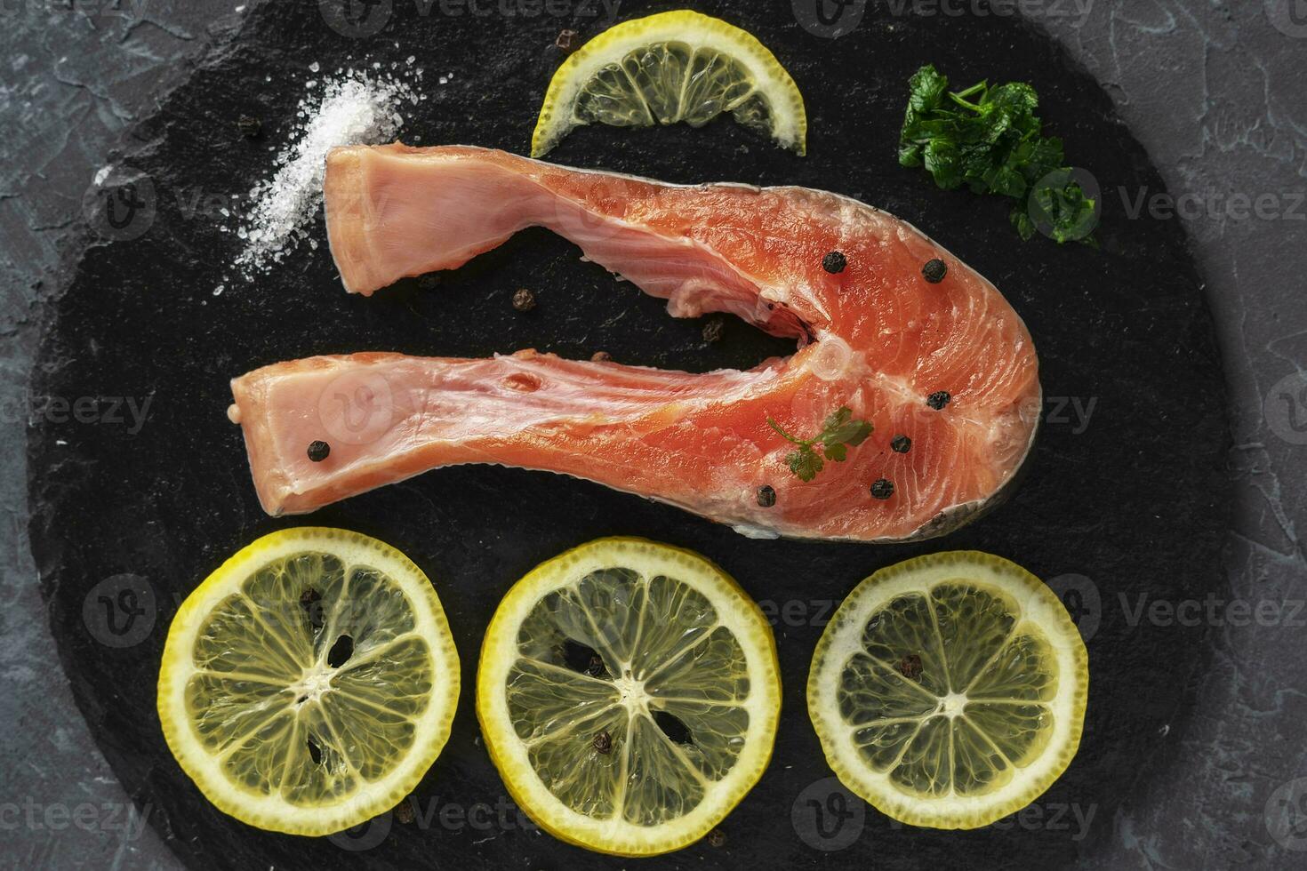 poisson steak avec herbes, épices et citron sur une ardoise noir planche photo