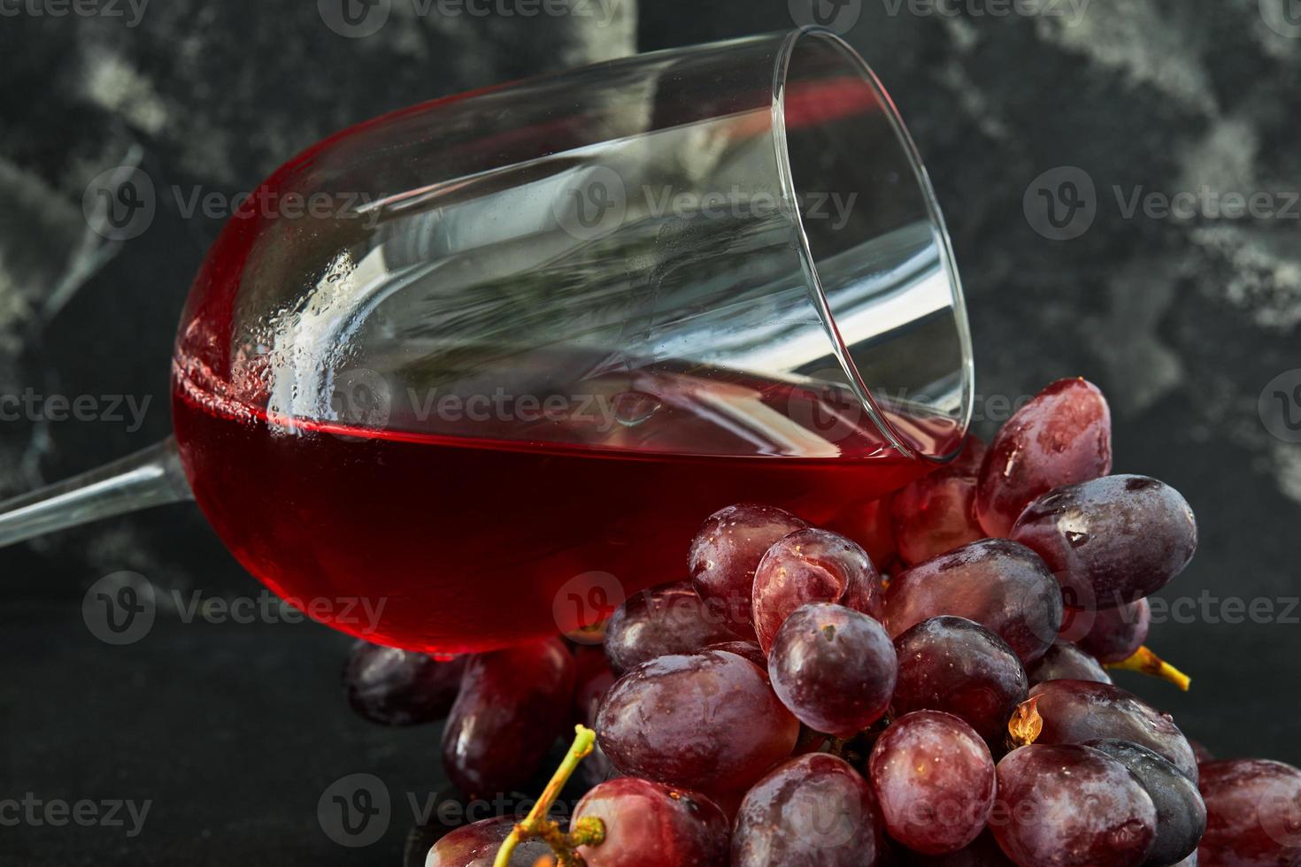 Verre de vin avec des raisins sur un support en bois noir photo