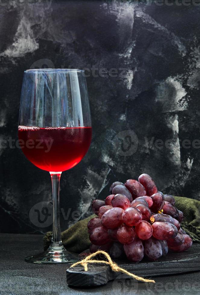 Verre de vin avec des raisins sur un support en bois noir photo