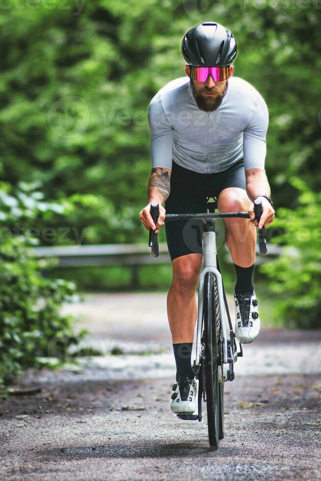 une homme sur une courses vélo sur une étroit route photo