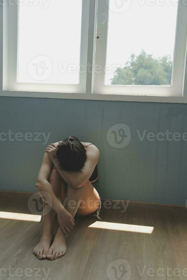 réfléchi fille séance sur seuil embrassement les genoux à la recherche à fenêtre, triste déprimé adolescent dépenses temps seul à maison, Jeune dérangé pensif femme sentiment solitaire ou frustré en pensant à propos problèmes photo