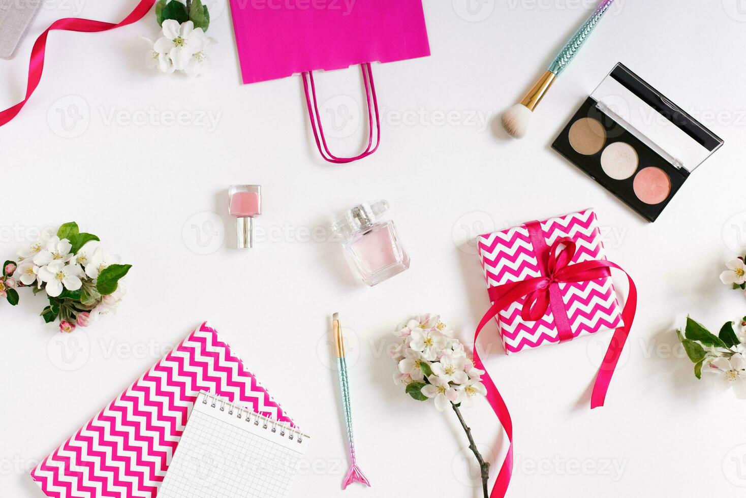 concept de une beauté Blog. accessoires pour aux femmes maquillage et délicat Pomme fleurs sur une blanc Contexte. plat appartement, Haut voir, aux femmes bureau, lieu de travail avec des cahiers dans rose photo